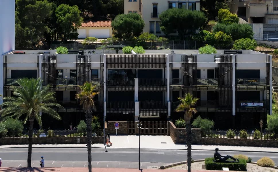 La façade de la résidence Cristal Plaisance et ses brise-soleil de bois, vue depuis le front de mer